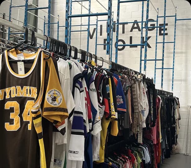 Vintage jerseys on warehouse rails with VINTAGE FOLK signage on the wall.